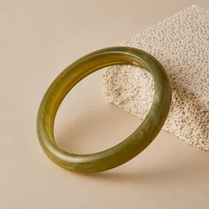 Detail of dark olive green acrylic resin bangle with white marbled texture and glossy finish