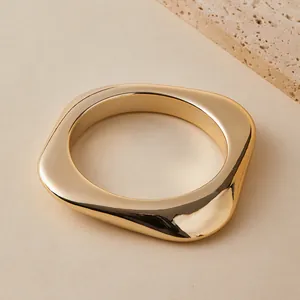 Makroaufnahme eines goldfarbenen klobigen quadratischen Armreifs mit Spiegelglanz
