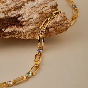 Detalle macro de pulsera de cadena bañada en oro de 18K con gemas de colores en madera