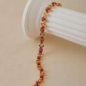 Detalle de pulsera de cadena de oro 18K con amuletos de ojo turco rojos sobre columna romana