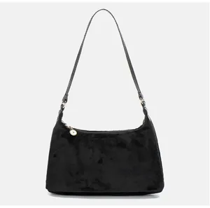 Detail of black suede shoulder bag featuring a smooth zipper and gold round metal charm