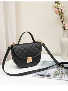 Close-up of black quilted saddle bag featuring golden metal clasp and top handle texture