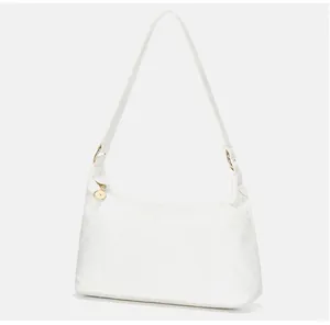 Detail of minimalist white faux leather baguette bag with elegant gold circular hardware