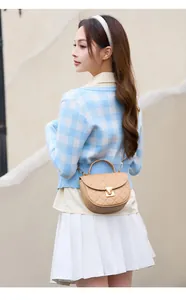 Close-up of khaki quilted saddle bag with metal clasp shown on a model outfit