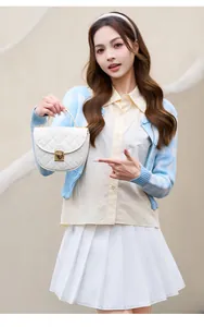 Detail of white quilted crossbody bag featuring elegant gold metal lock and top handle