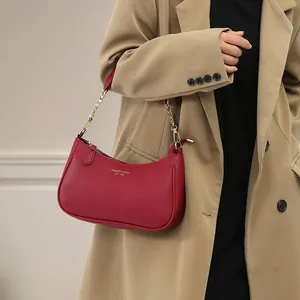 Litchi pattern wine red underarm bag with gold chain strap shown on a beige trench coat