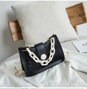 Dettaglio della borsa nera motivo coccodrillo con catena in resina crema e tracolla oro