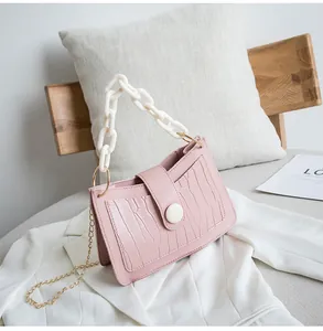 Dettaglio borsa rosa motivo coccodrillo con catena in acrilico bianco e tracolla oro