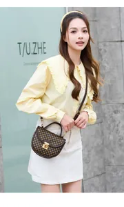 Detail of a brown geometric print handbag with a metal buckle lock on a yellow shirt