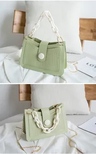 Dettaglio borsa verde chiaro motivo coccodrillo con catena bianca e tracolla in metallo