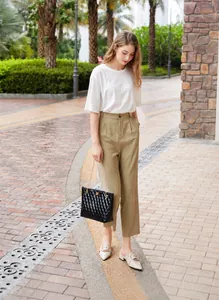 Street style view of a black quilted tote bag with golden chain strap and lock detail