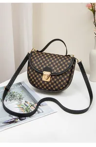 Detail of vintage patterned crossbody bag with golden metal clasp and leather handle