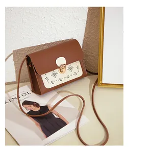 Détails des motifs floraux découpés au laser sur un sac bandoulière marron et blanc