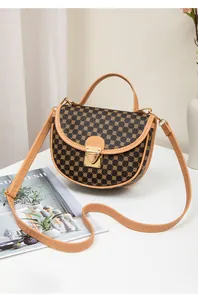 Detail of vintage patterned saddle bag with gold metal clasp and contrast stitching strap