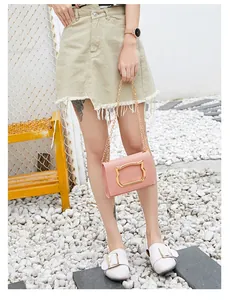 Pink leather chain bag featuring a distinctive gold cat-head metal clasp in a street setting