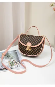 Close-up of vintage saddle bag with brown floral print and soft pink leather handle detail