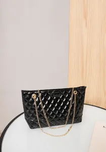Close-up of elegant black diamond quilted chain bag with shiny finish and gold hardware