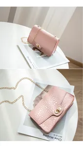 Détail du sac carré rose à motif crocodile avec chaîne dorée et fermoir métallique