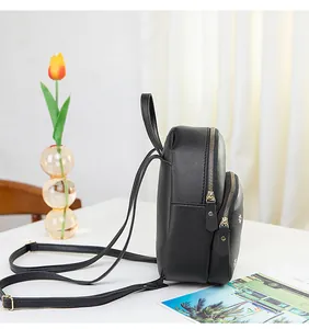 Detail of a black mini backpack with white daisy embroidery and golden metal zipper