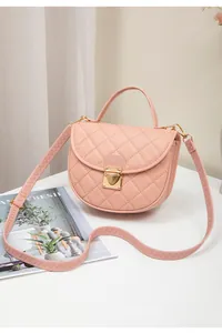 Close-up of pink quilted crossbody bag with gold metallic clasp and sawtooth strap detail