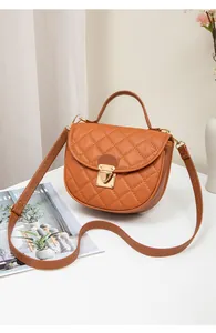 Detail of caramel orange quilted handbag with golden buckle and fine leather stitching