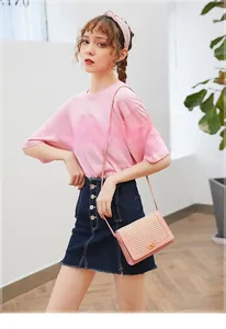 Detail view of pink crossbody bag with hollow grid pattern and gold rotary lock