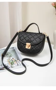 Detail of black quilted leather crossbody bag with golden hardware and round handle