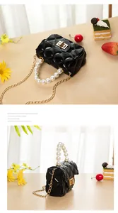 Detail of mini black quilted jelly bag with pearl handle and golden chain strap