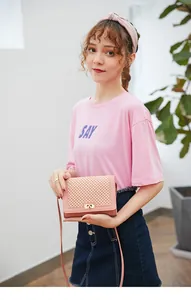 Detail view of pink crossbody bag featuring hollow grid texture and gold twist lock