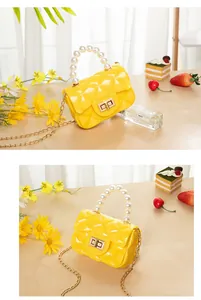 Detail of yellow quilted jelly mini bag featuring pearl handle and gold chain strap