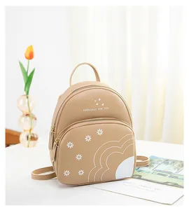 Detail of mini beige backpack featuring white daisy prints and zipper compartments