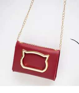 Detail of dark red chain bag featuring golden cat head hardware and metallic strap
