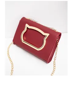 Detailed view of dark red crossbody bag with golden cat head metal piece and chain strap