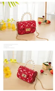 Detail of red quilted jelly bag with faux pearl handle and golden chain strap