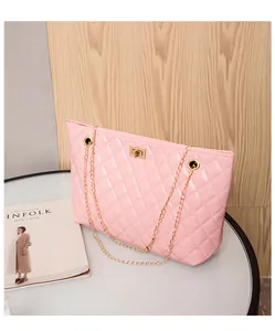 Close-up of pink patent leather shoulder bag with quilted pattern and gold metal twist lock