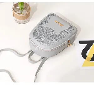Detail of light gray mini backpack featuring silver sequins and a leaf-shaped zipper pull