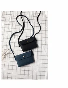 Detail view of mini crossbody bags in black and navy with textured leather and gold button