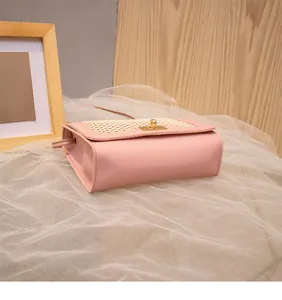 Detail of pink faux leather crossbody bag featuring woven texture and gold metal clasp