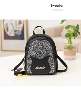 Detail of mini black leather backpack with silver sequins and golden leaf charm