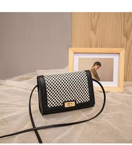 Detail of grid pattern small crossbody bag with golden twist lock and black leather trim