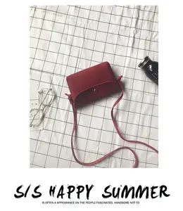 Detail of red litchi texture crossbody bag with gold magnetic buckle and slim strap