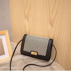Detail of grid pattern panel and gold twist lock on black rectangular crossbody bag