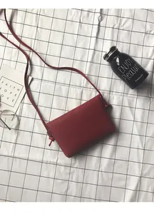 Detail view of red pebble leather crossbody bag with knot strap on white tablecloth