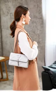 Detail of elegant V-quilted small square bag with metal logo and stylish chain strap