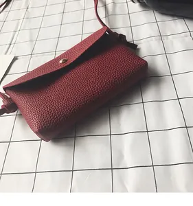 Close-up of wine red crossbody bag featuring litchi grain texture and gold metal clasp