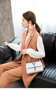 White quilted chain shoulder bag with metal V clasp and tassel on a model