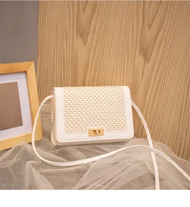Detail of white woven grid texture and golden twist lock on stylish crossbody small square bag