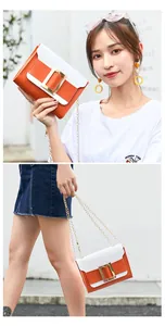 Détail du sac bandoulière orange et blanc avec boucle dorée et bandoulière chaîne