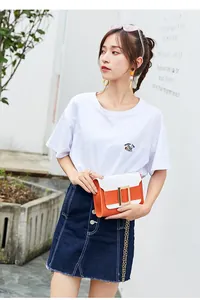 Détail du sac bandoulière blanc et orange avec boucle dorée et bandoulière en chaîne