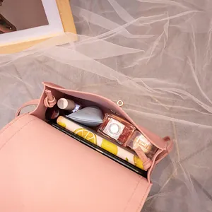Pink PU leather crossbody bag showing internal capacity with phone and cosmetics